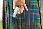 A man in a kilt holding a glass of whisky